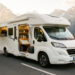 Camping-car moderne prêt à partir sur une route panoramique de montagne, avec des équipements soigneusement rangés et une lumière matinale chaleureuse.